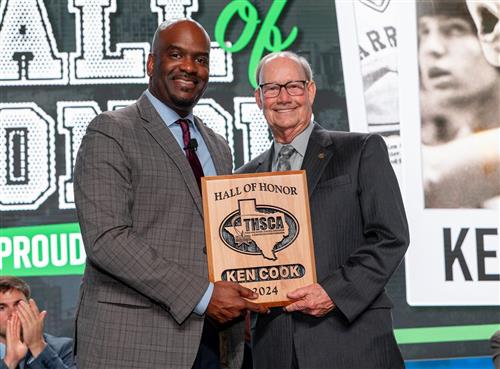 Two men stand together holding a plaque